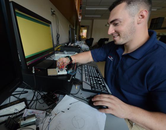 student working on a circuit board at a computer